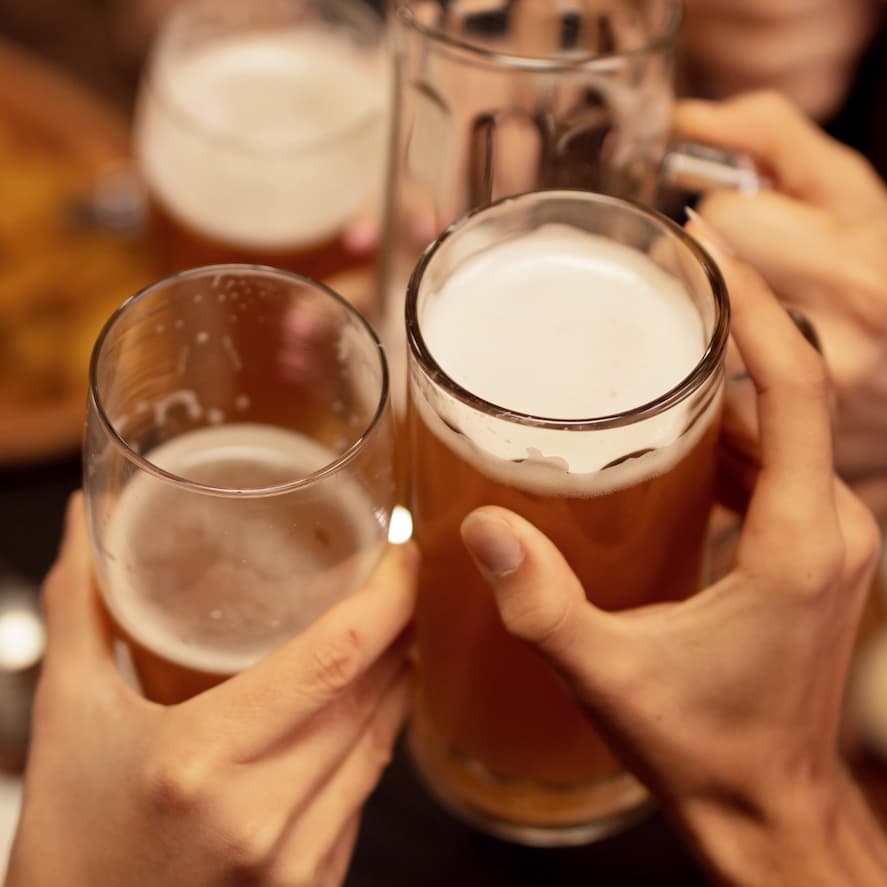 two people holding glasses of beer in their hands