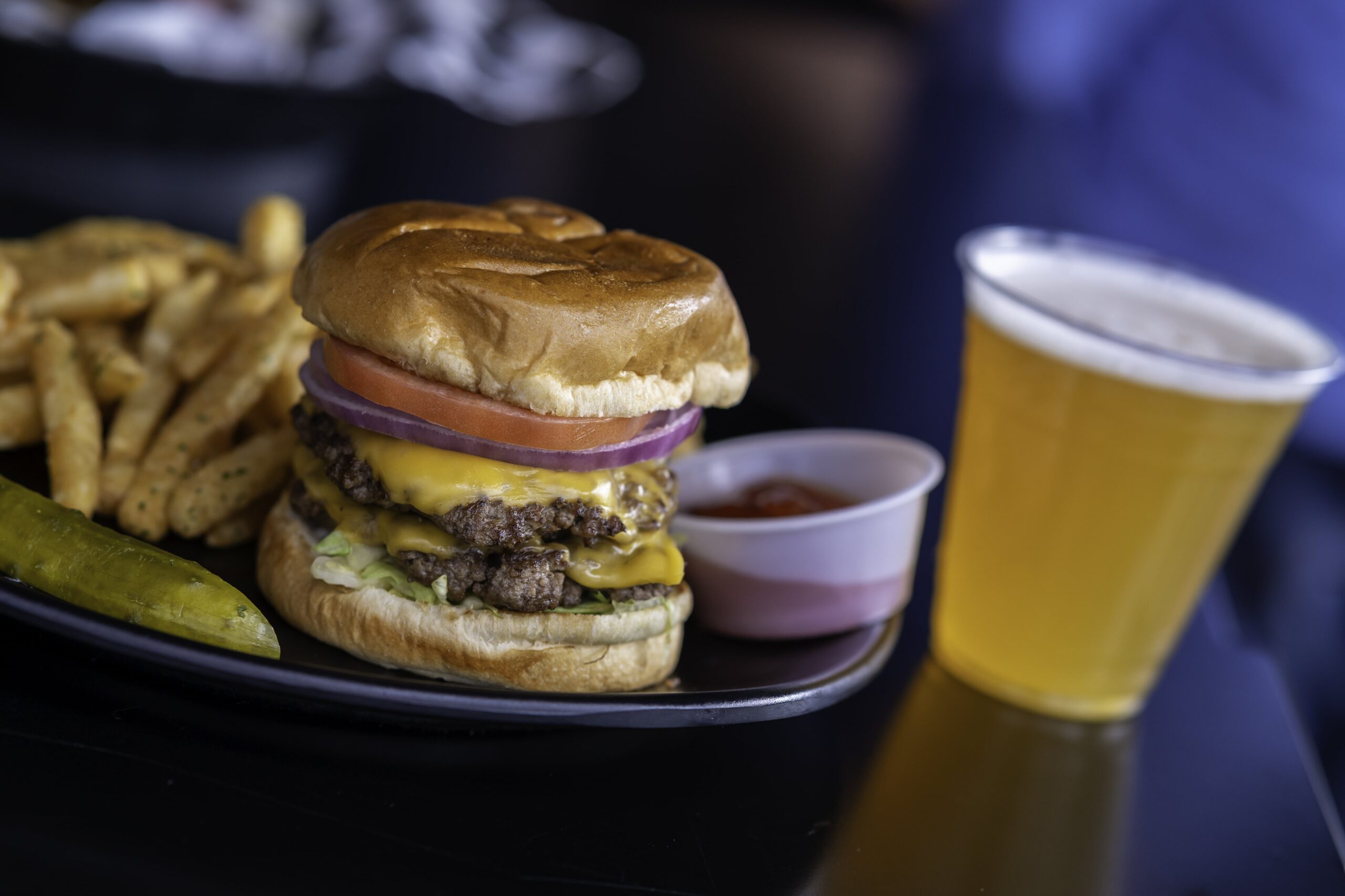 a hamburger and fries on a plate with a glass of beer