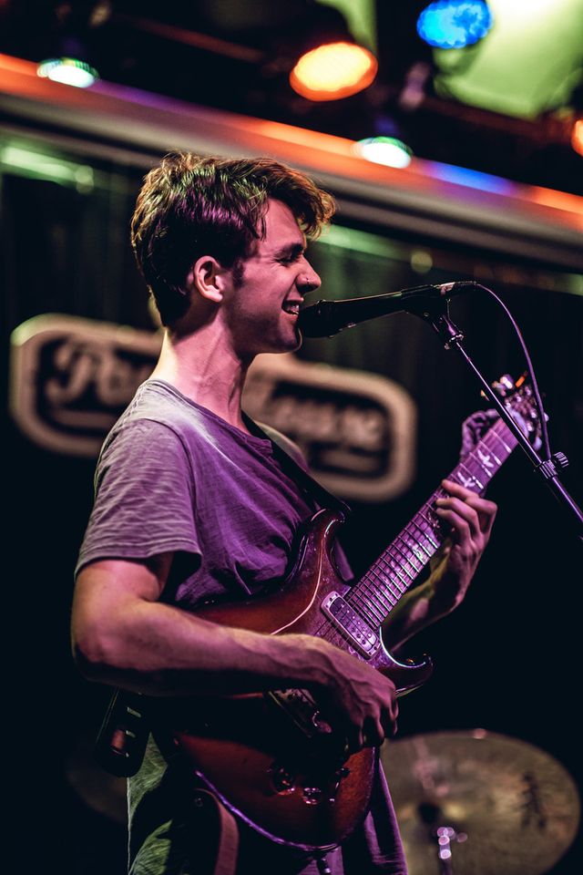 a man that is playing a guitar in front of a microphone